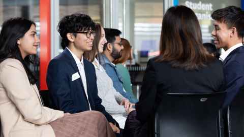 Group of students sitting in two lines facing each other in conversation.