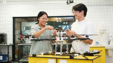 Engineering students working on drone in lab.