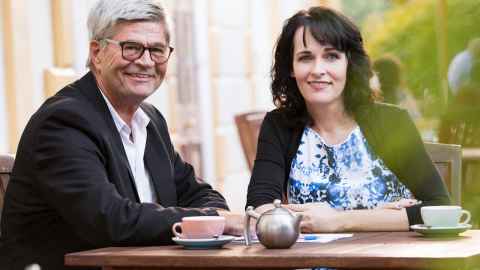 Two people sitting at a table and smiling.
