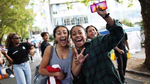 Two students waving at the camera