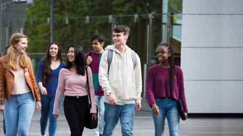 Group of happy students walking together outside