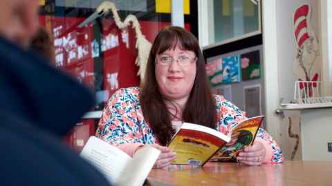 Danielle Wilson sitting in a classroom with a book