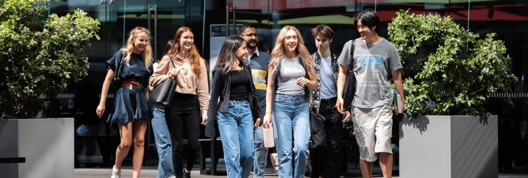 Group of seven students walking in a courtyard.