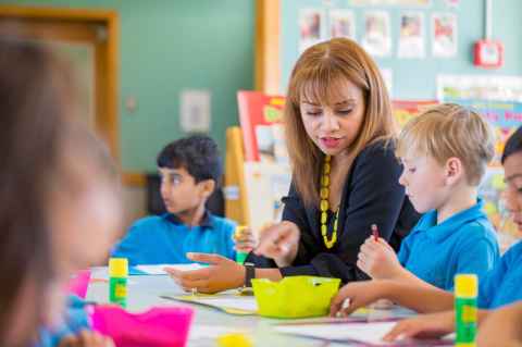 teacher sitting down with children at table