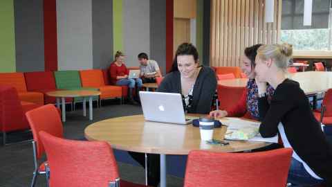 Three people looking at a laptop