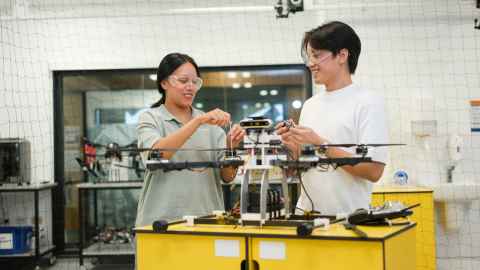 Engineering students working on drone in lab.