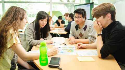 Students sitting at a table working together over papers