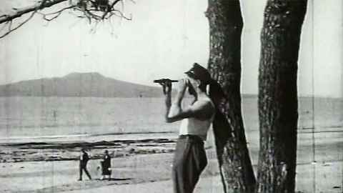 Black and white photo of man looking through telescope