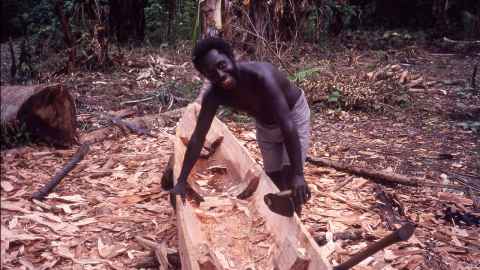 Image of a man in the Solomon Islands building a waka. 