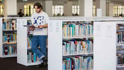 male student reading on General Library Level 1