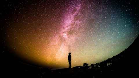 Silhouette of person staring up at night sky