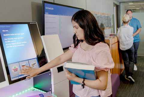 Person using a self checkout machine in the library