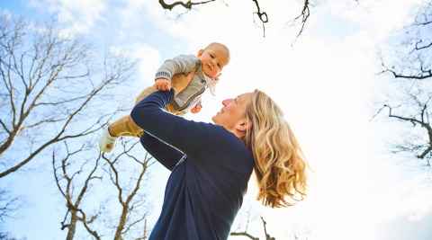 Mother holding her baby above her head