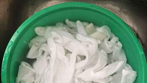 Green bucket full of white cotton gloves