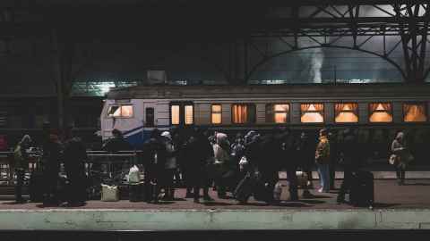 Ukrainian refugees board a train at night.