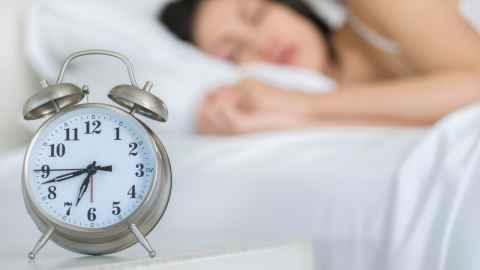 woman asleep with alarm clock 