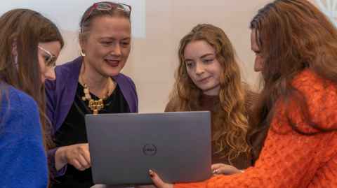 Four women around a laptop.