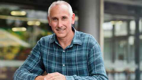 A man in a checked shirt smiling.