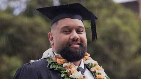 Picture of Feleti Lotulelei at graduation ceremony wearing his cap and floral lei