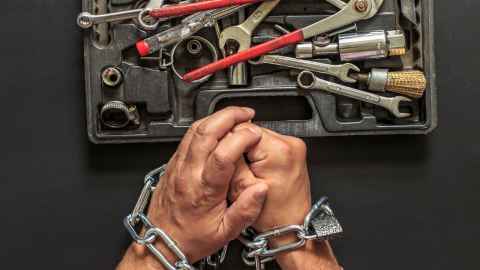 Padlocked hands in front of box of tools