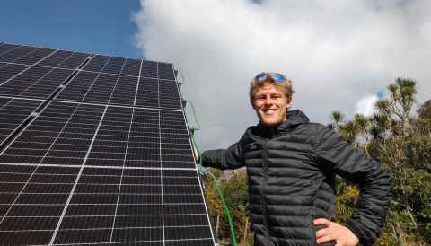 Jack pictured with a solar array he designed the foundations for, located near Anawhata Beach, Auckland.