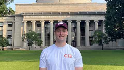 Peter Tremain stands on the grass in front of a classical columned building