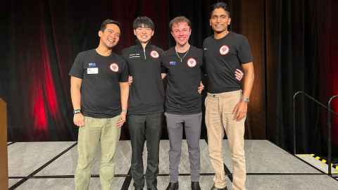 Two smiling male students flanked by smiling men