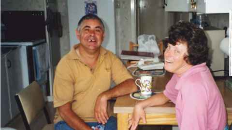 Julie and Carlo sit at the table having a cup of tea
