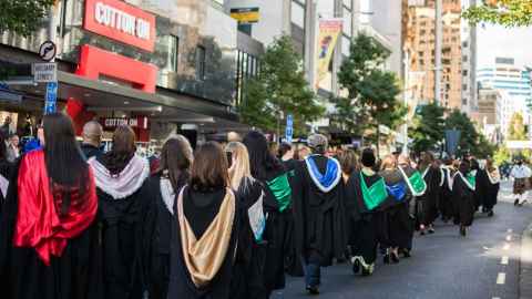 Graduates in gowns, rear view of parade Autumn graduation 2024