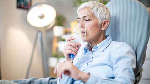 Older woman holding oxygen mask over her mouth