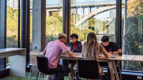 A group of students sitting at a table by a window, with views of Auckland.