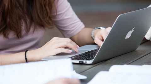 Person working at a laptop, closeup on their hands.