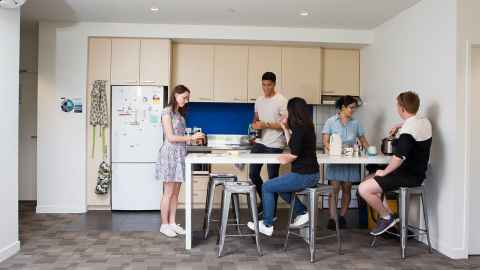 A group of students living in a shared flat and hanging out in the kitchen together.