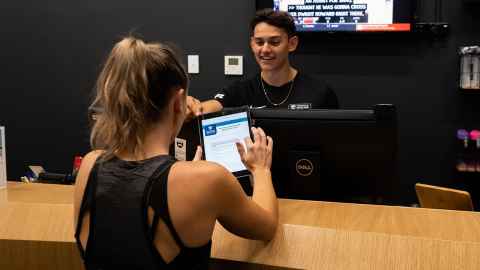 Person signs up for a recreation membership at the recreation reception desk with help from receptionist. 