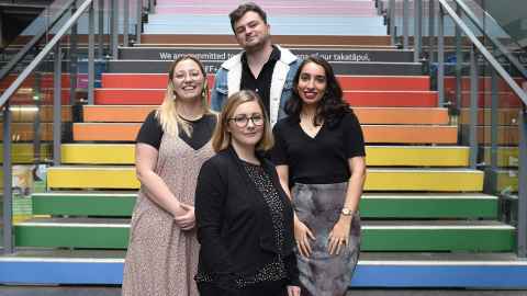image of staff members standing by rainbow staircase 