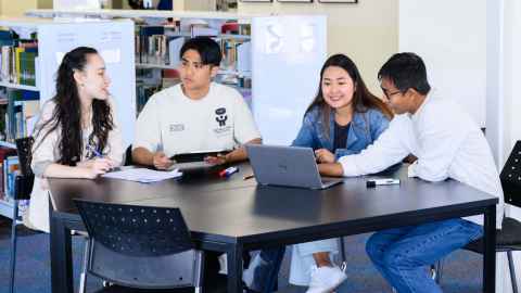 Group of four students seated, around a table