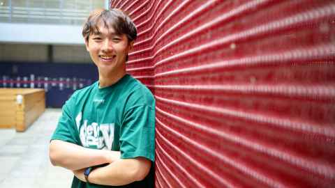 Smiling man standing next to a textured wall in red