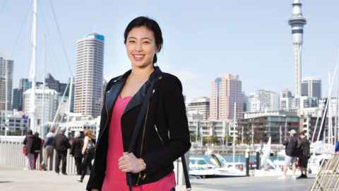 A smiling woman standing at Auckland's waterfront.